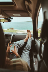woman sitting in car using her phone summer sea beach on background