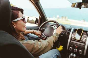 relaxed stylish woman in sunglasses driving car sea beach on background