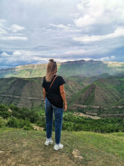 Fototapeta na wymiar A girl on the background of the village of Kurib in the Caucasus mountains, on top of a cliff. Dagestan Russia June 2021