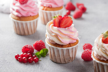 Pink cupcakes with cream and fresh berries