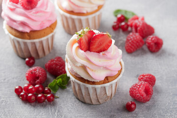 Pink cupcakes with cream and fresh berries