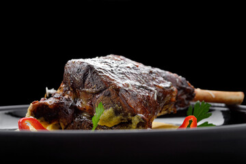 Fried leg of lamb with garnish and pepper, on a dark background
