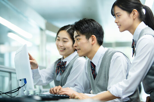 友達とパソコンを操作する男子高校生