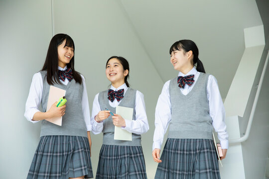 歩きながら談笑する笑顔の女子高校生たち
