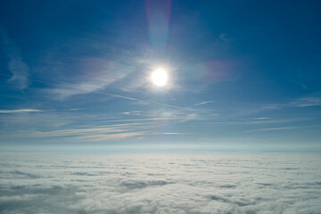 Aerial view from high altitude of earth covered with white puffy cumulus clouds on sunny day
