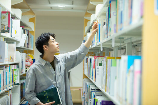 図書館で本を選ぶ男子学生