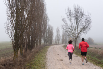 Couple running down a track on a foggy day - Powered by Adobe