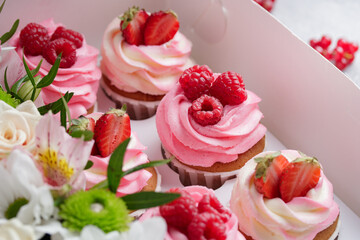 Pink cupcakes with cream and fresh berries