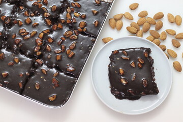 Slice of Texas sheet cake served on a plate. Buttery and chocolaty cake sliced to rectangular pieces inside the baking bin and scooped from it