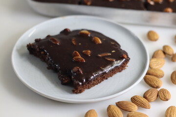Slice of Texas sheet cake served on a plate. Buttery and chocolaty cake sliced to rectangular pieces inside the baking bin and scooped from it