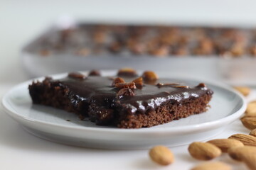 Slice of Texas sheet cake served on a plate. Buttery and chocolaty cake sliced to rectangular pieces inside the baking bin and scooped from it