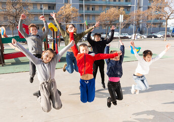 Group portrait of happy kids having fun on playground, jumping together