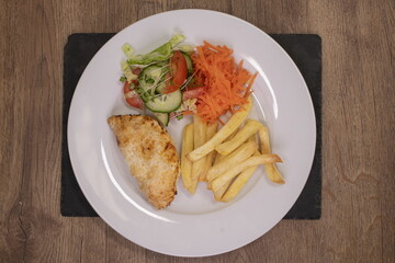 chips and salad including carrot and cucumber slice on a white plate 