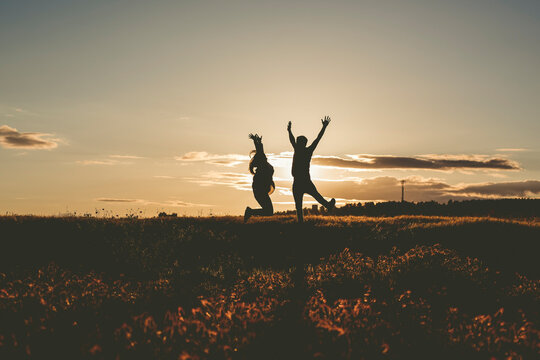 Silueta de novios a contraluz al atardecer bes&aacute;ndose y divirti&eacute;ndose. 
Concepto, amor de pareja, reci&eacute;n casados. 