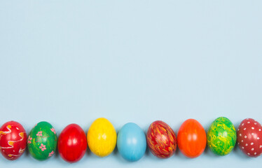 Easter background with handmade colored eggs on wooden a bright blue background. Frame and copy space.