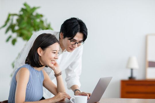 屋内でパソコンをしながら会話をするカップル