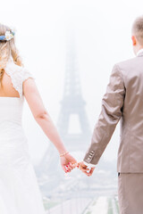 Fototapeta na wymiar Brautpaar Hand in hand vor dem Eiffelturm in Paris Frankreich