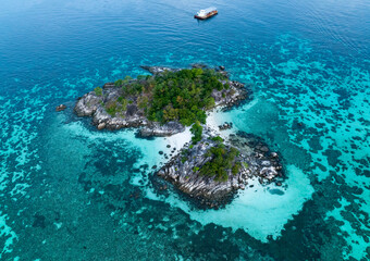 Above view of  the Tropical island beach with seashore as the tropical island in a coral reef ,blue and turquoise sea with local boat background