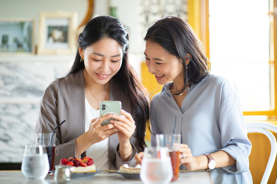 カフェでスマートフォンを見る女性2人