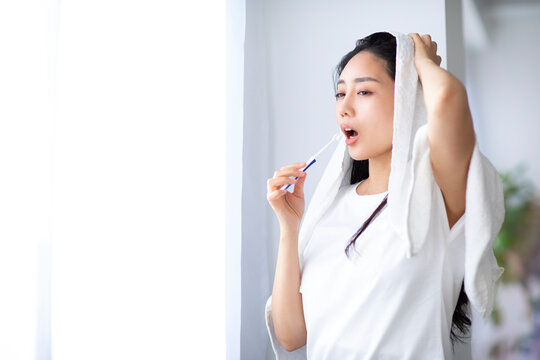 窓辺でで歯を磨く女性