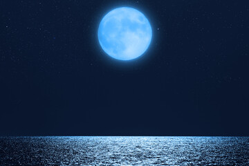 Fototapeta na wymiar Full Moon with starry skies rising above ocean horizon.