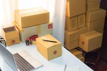 Desktop computer screen on white desk, interior of working room, work from home. home interior of open work space with white desk. packing parcel box for online shipping delivery. small home business.