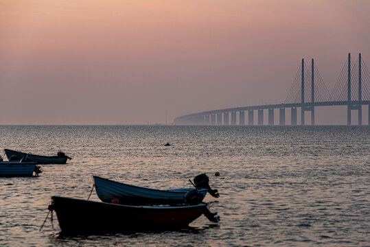 Romantic southern Sweden: Cozy Oresund Bridge detail at dusk with small boats. Close connection between Malmo and Copenhagen. Profound or deep link or bound illustration. Country boundaries or borders