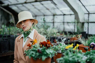 Portrait of asian girl in white cap and gypsophila flowers under her collar	sits in greenhouse 