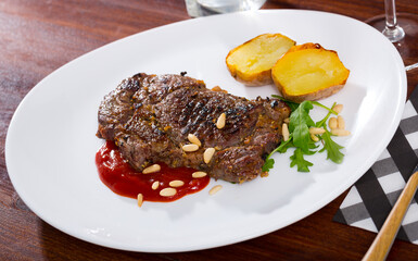 Delicious well done fried beef loin served with vegetable garnish of baked potato, tomato sauce and pine nuts