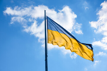 Flag of Ukraine flutters in blue sky. Large yellow blue Ukrainian national state flag. War