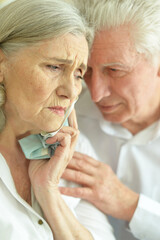 Beautiful sad senior couple posing at home