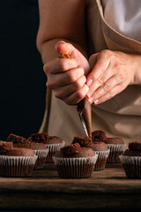 Chef fills the cupcakes with chocolate cream from the confectionery bag. Process of making muffins....