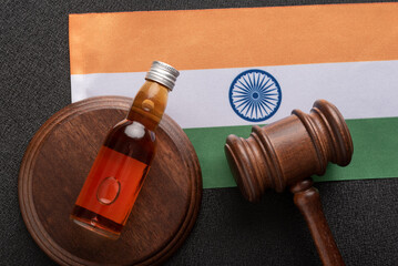 Bottle of alcohol and judge gavel as symbol of law and above flag of india. Top view close-up....