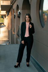Obraz premium Lady director wearing black suit and heels. Business woman in jacket and trousers. Formal business clothing.