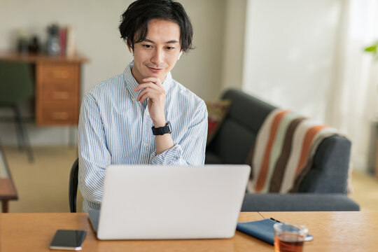 カジュアルな空間でノートPCの画面に向かって話しかける男性