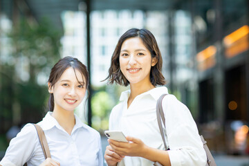 スマートフォンを持って笑顔を見せるビジネスウーマン2人