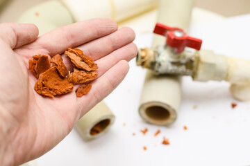 Rusty dirt and scale from polypropylene water pipes in a man's hand. Selective focus on a pile of...