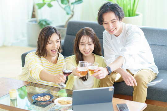 タブレットPCの画面に向かって乾杯のポーズをする男女