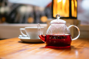 Glass teapot and a cup of tea on a table in a restaurant.