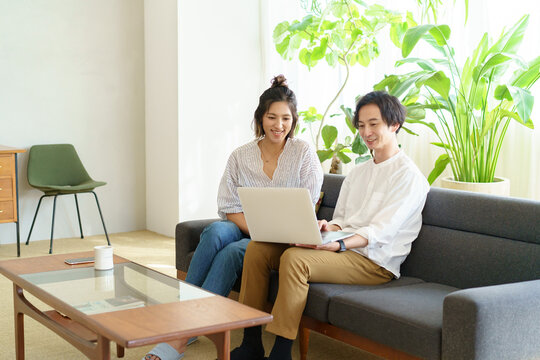 部屋でノートパソコンの画面を見る男女
