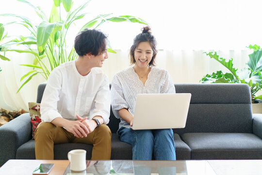 部屋でノートパソコンの画面を見る男女