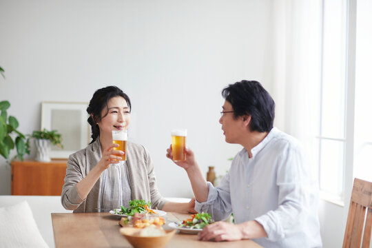 ビールを飲みながら食事をする夫婦