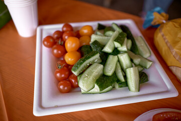 Organic vegetables: cherry tomatoes, cucumbers on the table. Healthy snacks. Summer picnic. Copy space