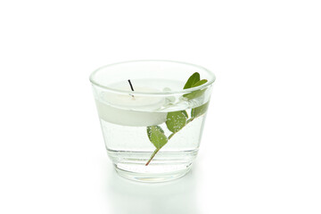 Glass of water with candle and twig isolated on white background