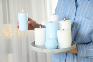 Woman holds tray with blue and white aroma candles