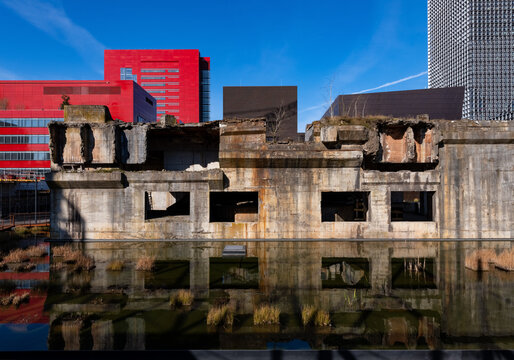 Panorama of Belval historic industrial site in Esch sur Alzette Luxemburg with contrasting with new buildings. Concrete remains of steel mill with blast furnace surrounded by artificial  pond.
