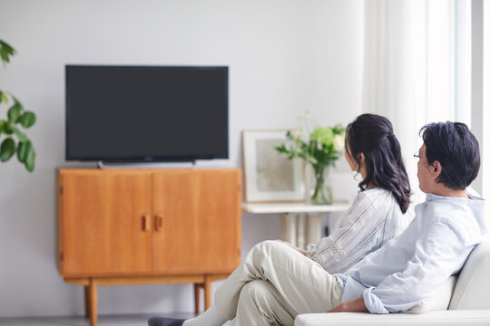 リビングでテレビを見ながらくつろぐ夫婦の後ろ姿