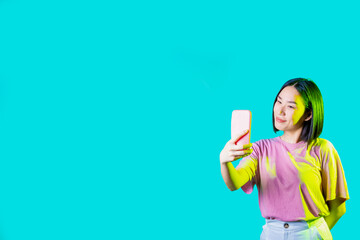 Young asiatic woman isolated using smartphone taking selfie