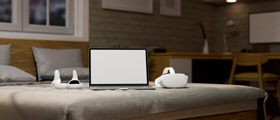 Bedroom background with modern gadgets concept, Laptop white screen mockup and VR headset
