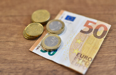 50 euros and metal coins and cents on a brown wooden table